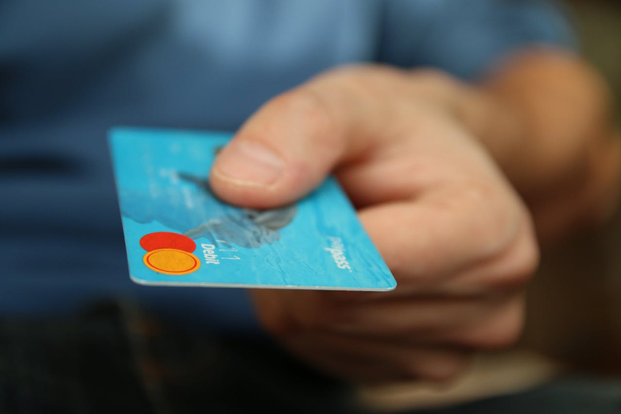services-02 A close-up shot of a hand offering a blue debit card for payment.