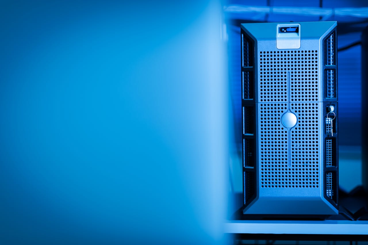 services-01 Close-up of a modern server unit in a blue-lit data center environment.